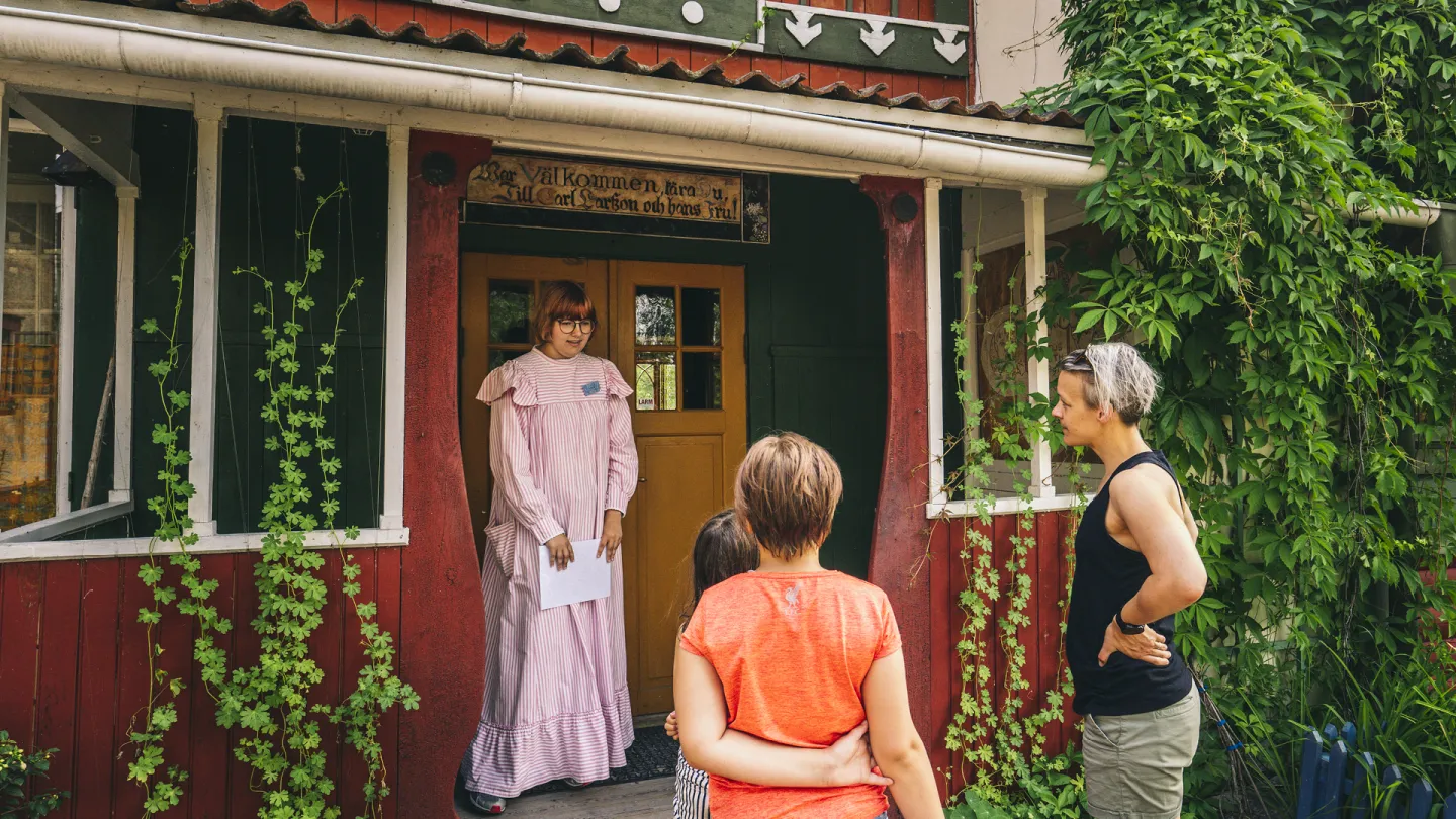 Guide som välkomnar besökare för en guidad tur inne i Carl Larsson-gården.